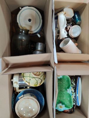 two boxes with cups and bowls in them on the floor
