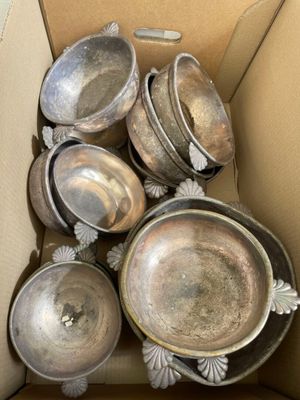 a cardboard box with a bunch of silver dishes inside of it