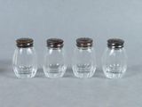quatre petites salières et poivrières en verre alignées en rang