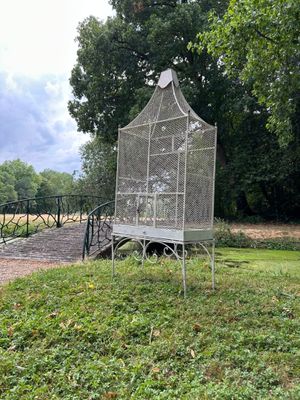 une cage à oiseaux posée sur un banc au milieu d'un champ