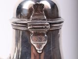 a silver coffee pot with a lid on a table