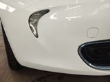 the front end of a white sports car in a showroom