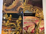 deux livres posés sur une table, à côté d'une chaise dorée et d'une horloge