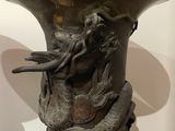 a bronze vase with a bird on it sitting on a table