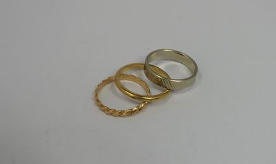 three gold rings on a white surface