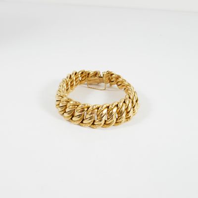 gros plan d'un bracelet en or sur une surface blanche