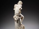 a white statue of a man sitting on a pillar with a dog