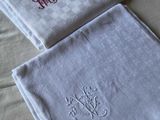 Deux serviettes ornées de monogrammes sont posées sur un lit.