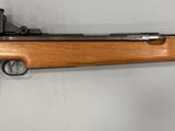 un fusil accroché au mur d'une pièce aux murs blancs