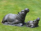 une statue représentant un hippopotame et son petit allongés dans l'herbe