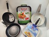 several pans and frying pans are on a counter top