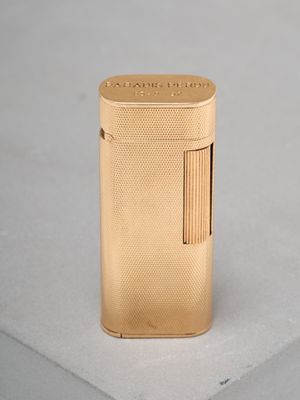 gold lighter sitting on top of a white surface on a table