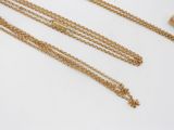 three gold chain necklaces with a tassel on a white surface