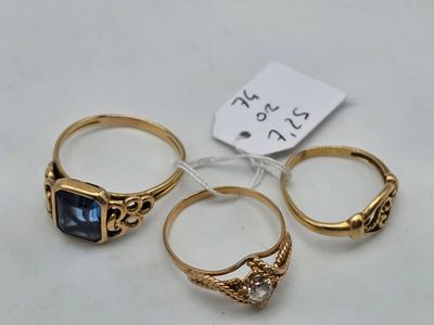 trois bagues en or ornées de pierres bleues et d’une étiquette sur un fond blanc