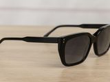 a pair of black sunglasses sitting on top of a wooden table