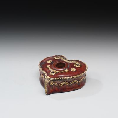 une vieille boîte rouge et dorée en forme de cœur posée sur une table