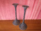two metal candlesticks sitting on a wooden table