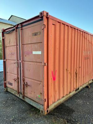 a red shipping container sitting in the middle of a gravel lot