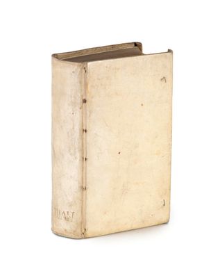 un vieux livre posé sur une table blanche à côté d'un mur blanc