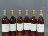 six bouteilles de vin sont alignées sur une table
