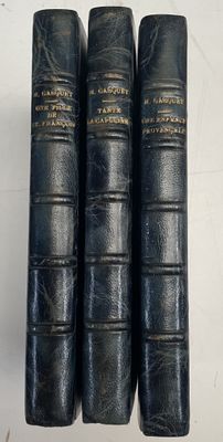 trois livres en cuir noir posés sur une table blanche