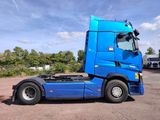 a blue semi truck parked in a lot with trees in the background