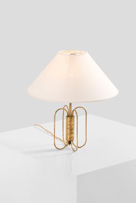 a gold table lamp with a white shade on top of a white table