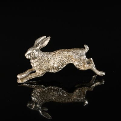 une figurine de lapin en argent posée sur une surface noire