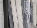 de nombreux matelas empilés les uns à côté des autres devant un immeuble