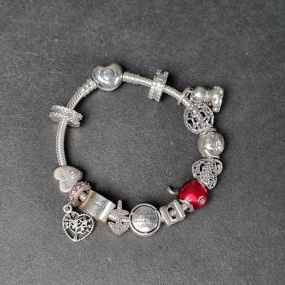 un gros plan sur un bracelet en argent orné de perles rouges et de breloques