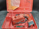 une vieille boîte à outils rouge contenant une perceuse filaire et d'autres outils