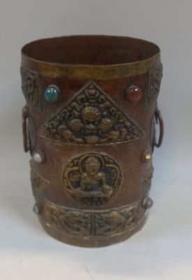 une tasse en métal ornée d'un motif sur un fond blanc