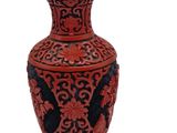 a red vase with a blue lid sitting on a white surface