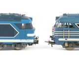 two toy trains on a white surface one is blue and the other is silver