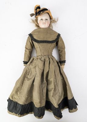une poupée à l'ancienne, vêtue d'une robe marron et coiffée d'un chapeau, posée sur un fond blanc