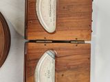 two wooden clocks on a white table with a clock on the wall