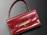 a red handbag with a gold handle on a black surface