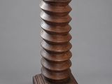 une grande sculpture en bois représentant une colonne en spirale, reposant sur un socle en bois