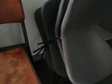 a laptop computer sitting on top of a desk next to a stack of chairs