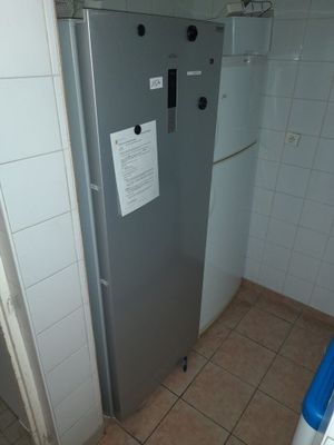 un réfrigérateur dans un coin de la salle de bains, avec une affiche sur la porte