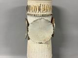 a white vase with a wooden handle on a gray surface