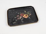 un plateau noir orné de fleurs, posé sur une surface blanche