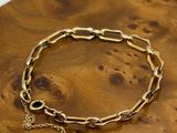 a close up of a gold bracelet on a wooden table
