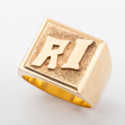 un gros plan d'une bague en or sur laquelle figure la lettre « r »