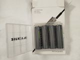 four batteries in a clear box on a white surface