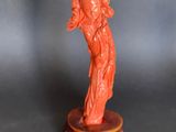 an orange statue of a woman holding a baby on a wooden base