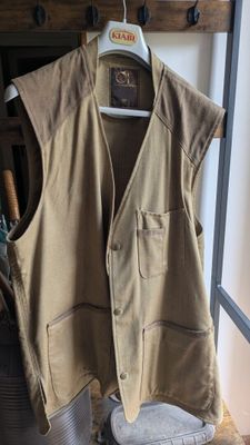 un gilet beige suspendu à un portant dans une pièce