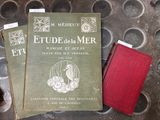 trois livres posés sur une table en métal, à côté d'un livre rouge