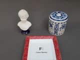 une assiette rouge, une assiette blanche et une assiette bleue et blanche sur laquelle figure le buste d'un homme