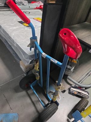un diable bleu avec une poignée rouge dans une pièce